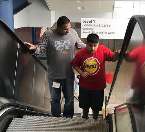 MUHSEN volunteer is ushering a boy with special needs up the escalator.