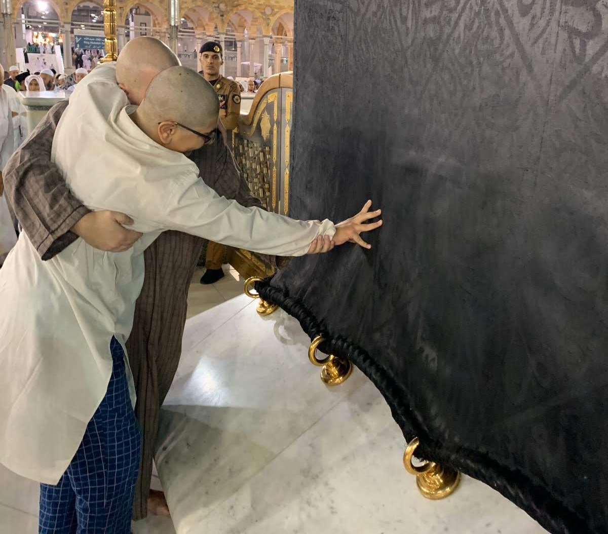 muhsen volunteer helping boy with special needs touch the kabah