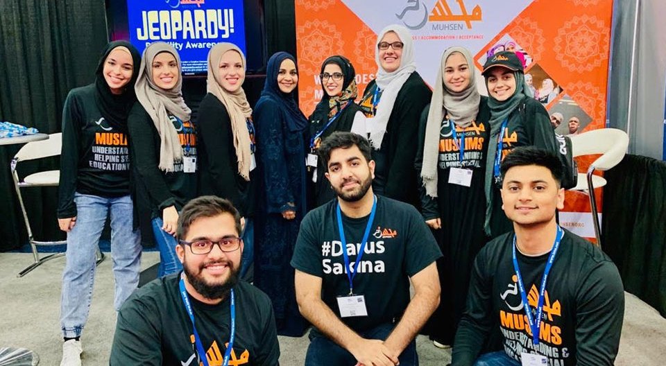 Joohi Tahir and 10 volunteers are posing in front of the MUHSEN booth during the ICNA convention.