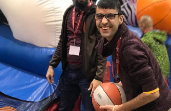 A brother with special needs smiling holding a basketball.