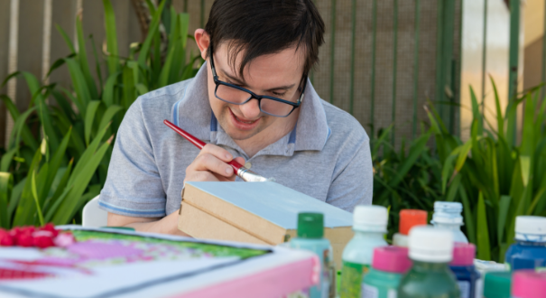 Brother with special needs smiling and painting a box