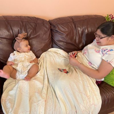 Woman and baby sitting on a couch smiling at each other
